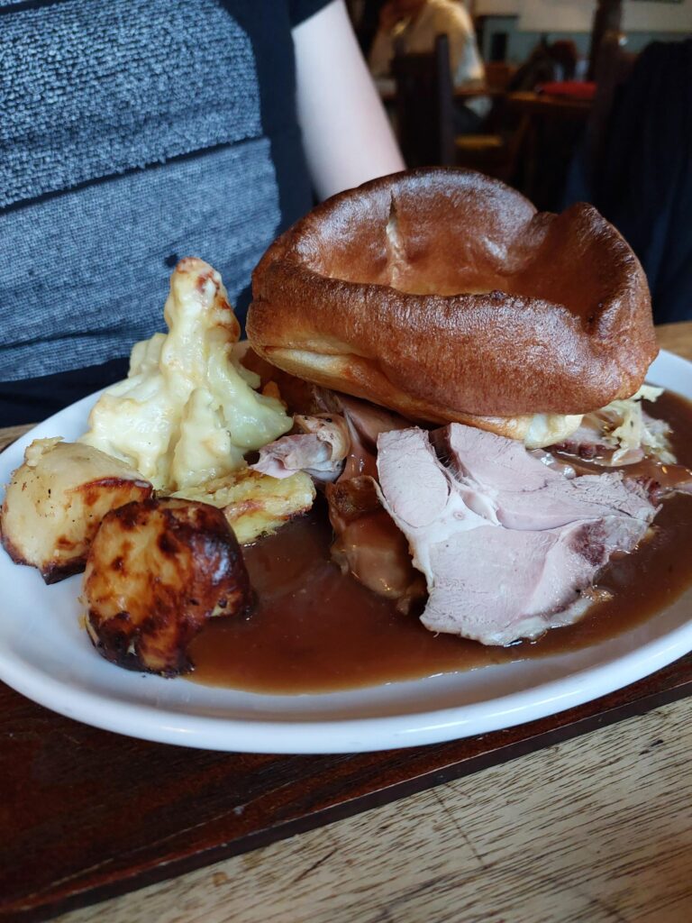 A large roast dinner plate, with slices of lamb, potatoes, cauliflower cheese and a Yorkshire pudding