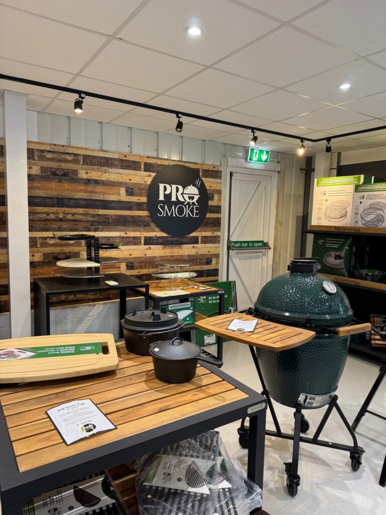 Internal of shop with Big Green Egg kamado cooker with accessories behind on shelves
